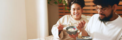 Woman and man eating cottage cheese in bed