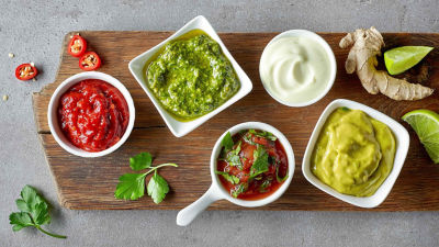 Different sauces in bowls on a chooping board