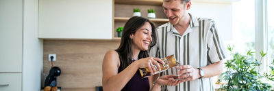 Couple in kitchen, woman pouring protein milk into glass