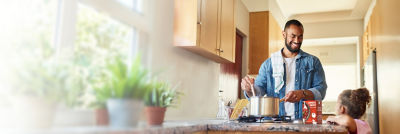 Father and child cooking in kitchen, tomato sauce in Tetra Recart carton
