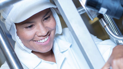 Woman operator in protection gear smiling in factory