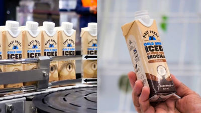 Cold brew iced latte in Tetra Prisma Aseptic cartons on distribution line and hand holding carton package