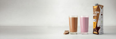 Two glasses with flavoured milk, proteing milk in Tetra Prisma Aseptic carton package