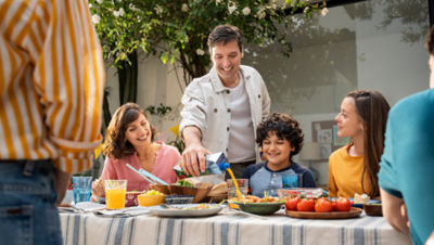 Family enjoying a meal outside, dad pouring juice from a Tetra Pak container