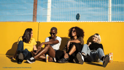 four people sitting by a wall