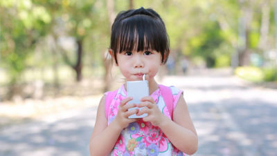 Une petite fille chinoise en train de boire, un emballage en carton Tetra Brik Aseptic