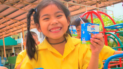 Two kids smiling and drinking milk from Tetra Pak packages