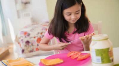 A girl spreading mayonnaise on a sandwich