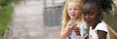 Two girls drinking from carton with a straw