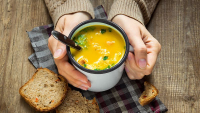 hands holding a cup of soup