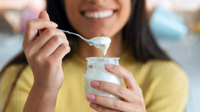 Woman holding jar of plain yoghurt smiling