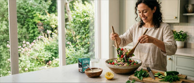 Woman preparing salad in kitchen, tuna in Tetra Recart carton package