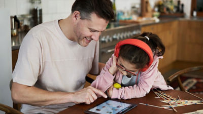 Un père et une fille en train de regarder un iPad