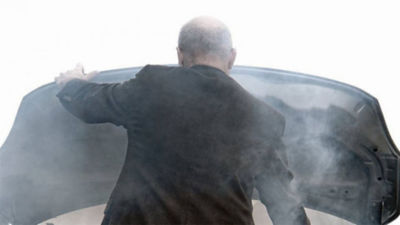 Uomo che tiene in mano il cofano di un'auto