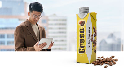 Man with tablet, frappuccino coffee drink in Tetra Prisma Aseptic carton package