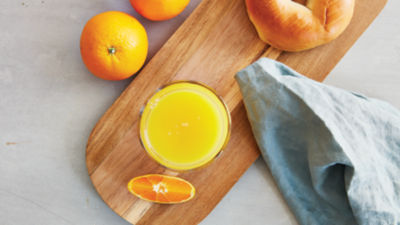 Orange Juice and bagel on wooden tray