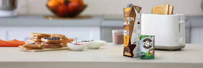 Chocolate milk and protein milk in carton packages and toast on kitchen counter