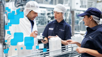 Persone in una centrale del latte mentre esaminano delle confezioni in cartone