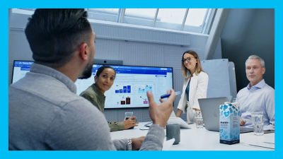 People in meeting discussing, data on screen