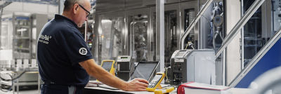 Service engineer with laptop, calibrating machine