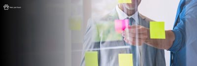 Man putting post-it notes on glass wall