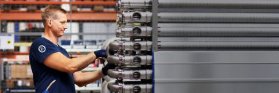 Trabalhador realizando manutenção em equipamento de trocador de calor industrial