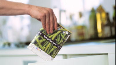 Someone holding empty carton over recycling bin