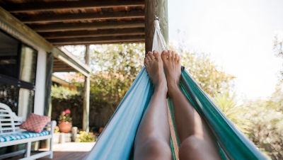Person resting in a hammock on their porch.