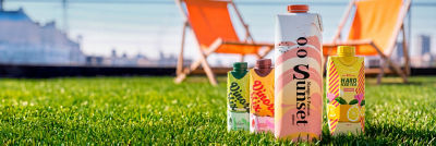 RTD alcoholic beverages in carton on the grass with beach chairs in the background