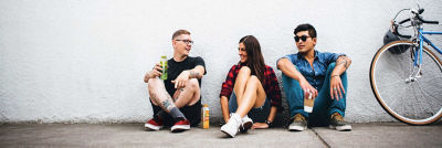 Two men and a woman taking a break, sitting and leaning against a wall