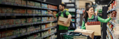 Store staff unpacking groceries, Tetra Recart cartons on shelf