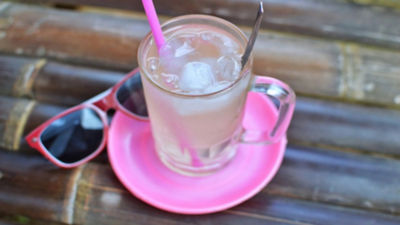 Red sunglasses next to drinking glass on pink plate 