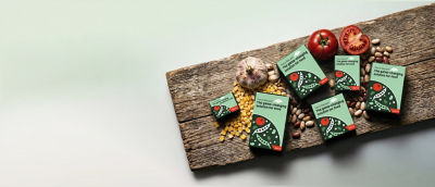 Tetra Recart carton packages, corn, beans and fresh tomatoes on wooden cutting board