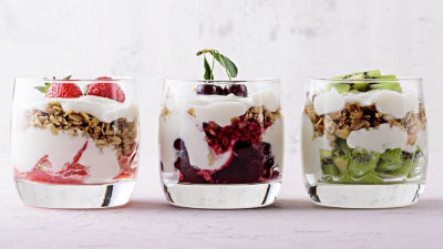 three glass with plant-based yoghurt-style toped with granola, strawberry, kiwi and cherries