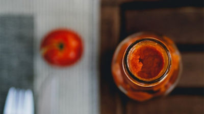 Tomato next to jar of tomato sauce