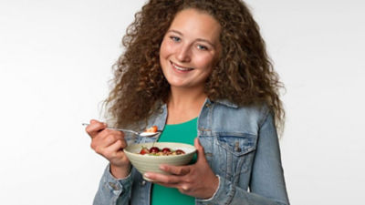 En kvinna som äter yoghurt med bär ur en skål