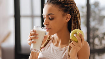 Woman drinking protein drink and eating apple