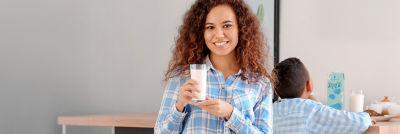Woman holding a glass of milk, young boy in background