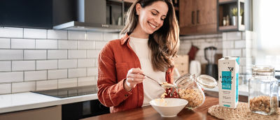 Woman in kitchen making breakfast, cereals and milk in carton package
