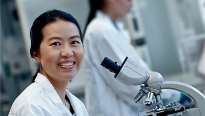 A woman in a lab coat with a microscope
