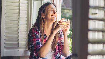 Femme assise près d'une fenêtre dégustant une boisson sans alcool