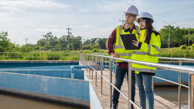 Man and woman with clipboard  in high vis jackets at water treatment facility