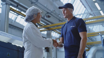 two people shaking hands at a factory 