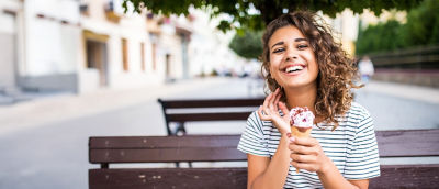 Una mujer toma un helado sentada en un banco