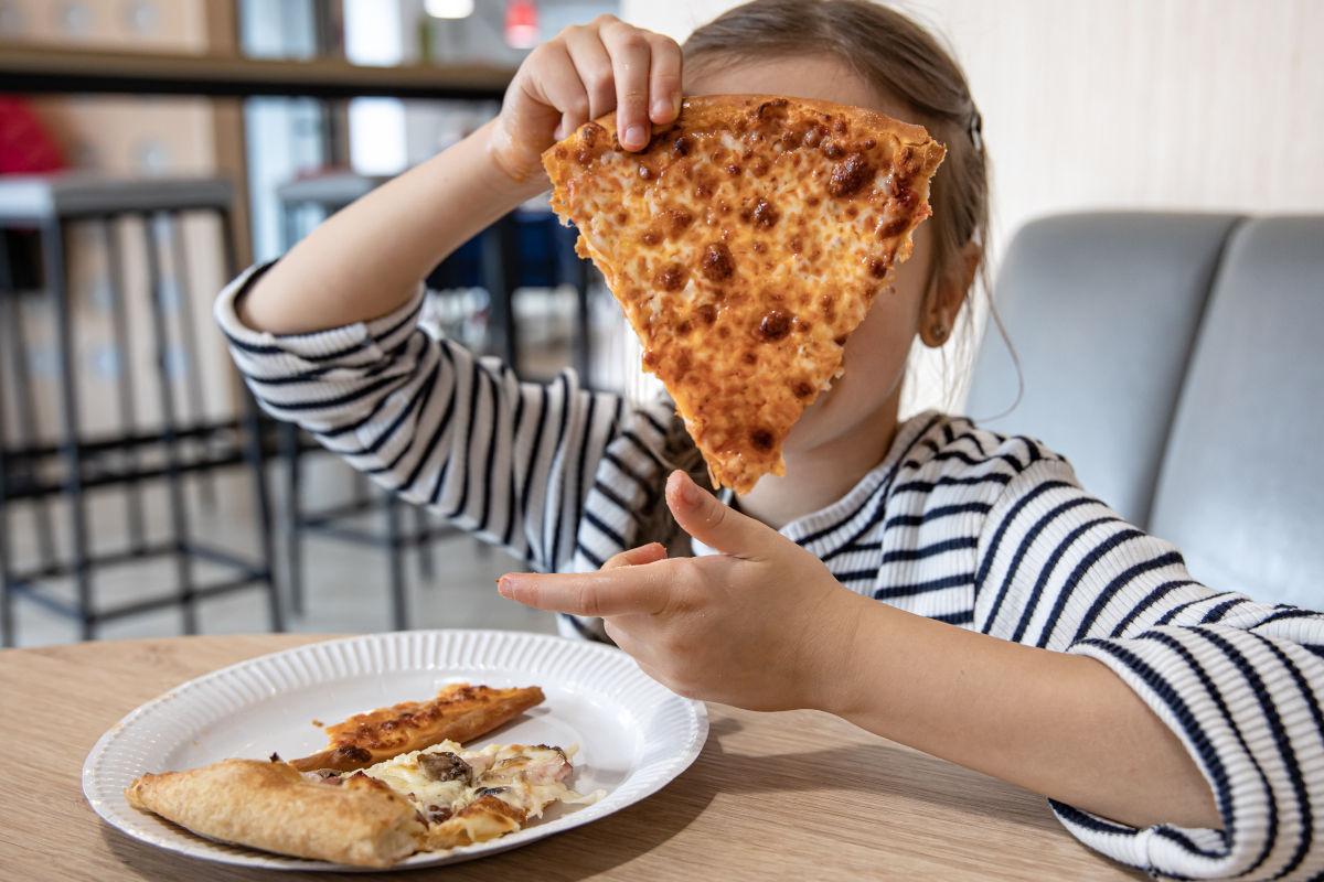 bambina con pezzo di pizza