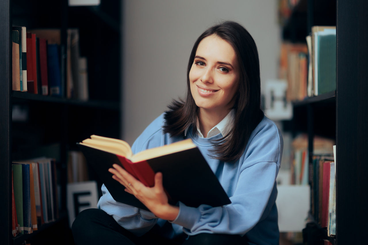 Smart young person sitting a bookstore looking for textbooks