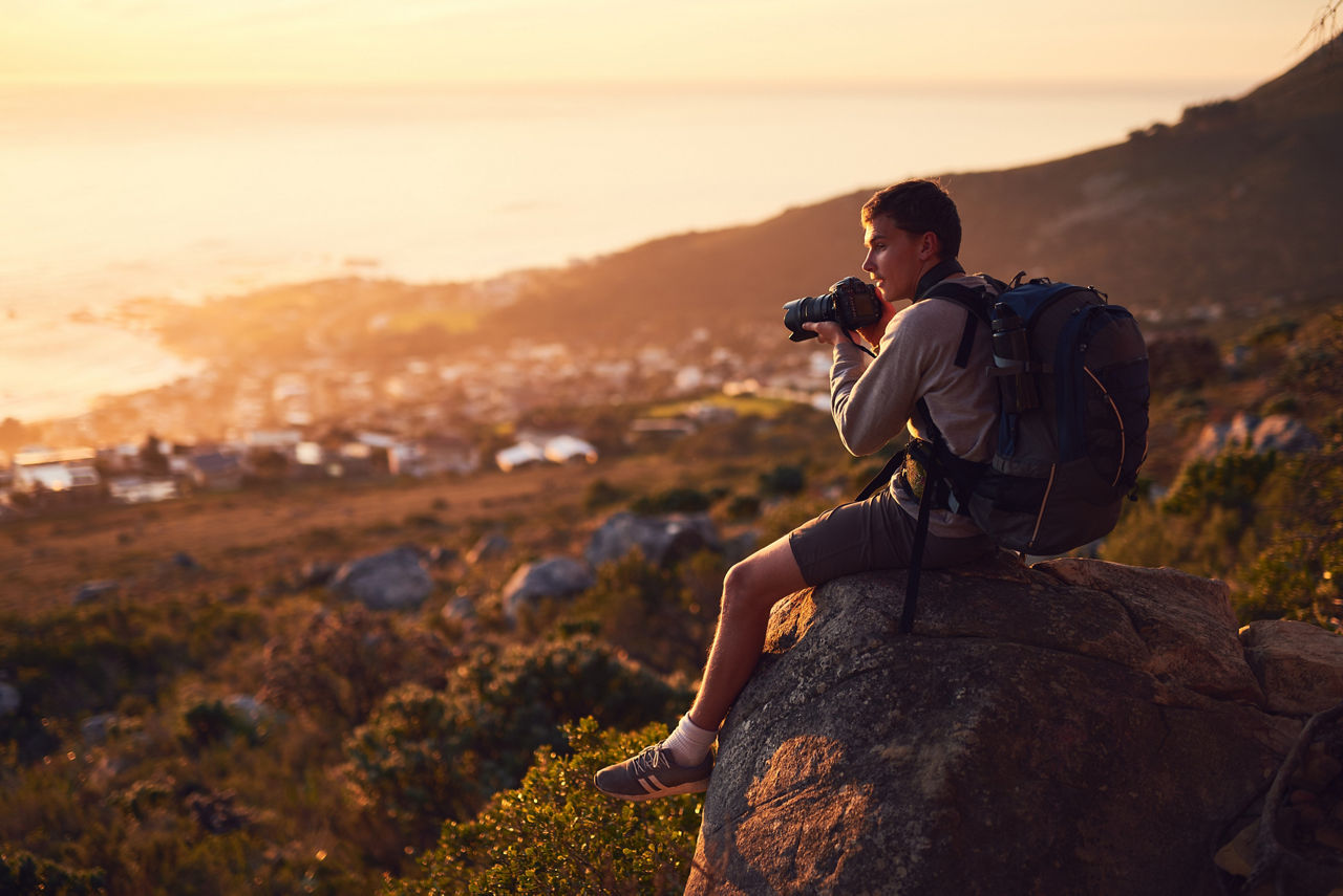 Shot of a young photographer taking a picture from the top of a mountain