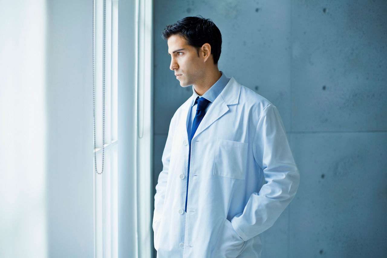Thoughtful doctor looking through a window.
