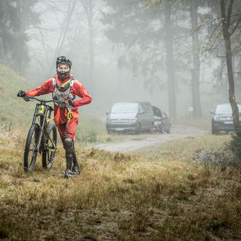 Christian Junker starts his mountain bike tour, in the background are several parked VW cars
