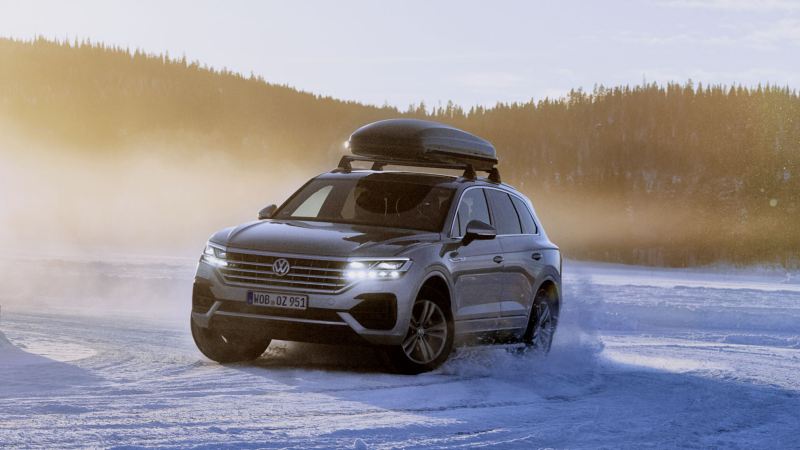 Volkswagen Touareg con un baúl de techo circulando por la nieve